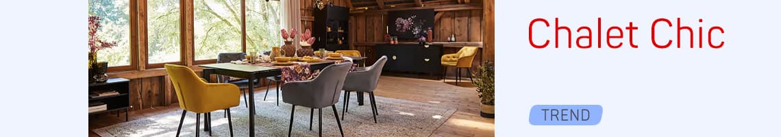 Chalet Chic Trend – Essbereich mit bunten Polsterstühlen und gedecktem Tisch in holzverkleidetem Raum mit großen Fenstern