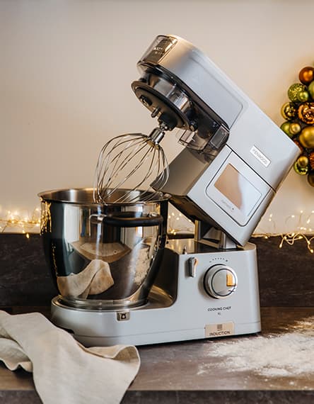 Festlich gedeckter Tisch mit Kerzen, roten Beeren und Geschirr, Besteck und Gläsern auf runden Platzsets