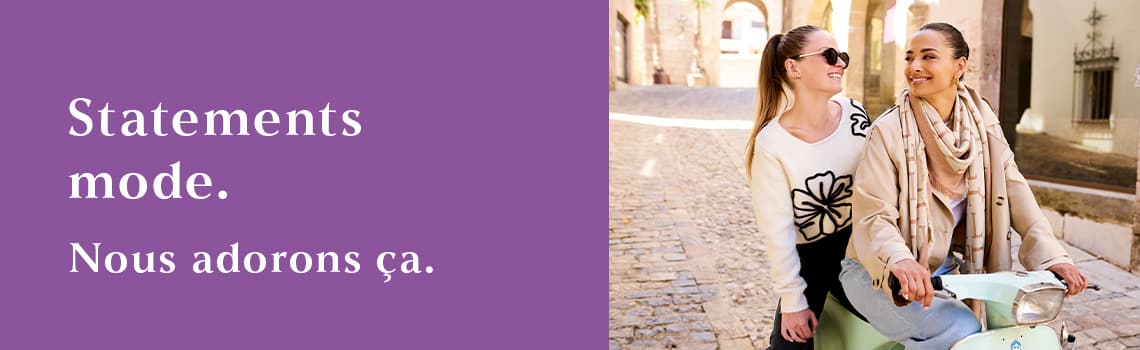 Fashion Statements. Lieben Wir. – Zwei Personen in modischer Kleidung sitzen auf einem Motorroller auf einer gepflasterten Strasse