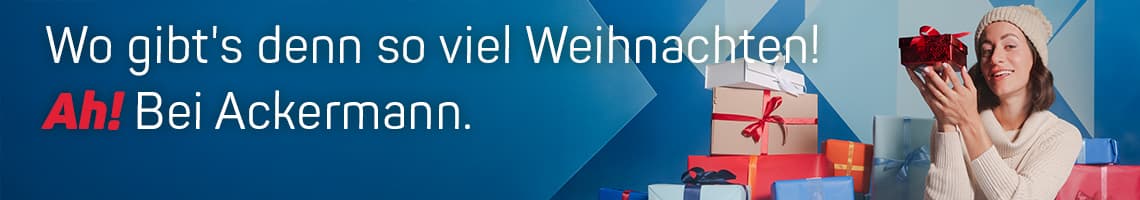 Wo gibt's denn so viel Weihnachten! Ah! Bei Ackermann. Frau hält Geschenk, umgeben von gestapelten Weihnachtsgeschenken