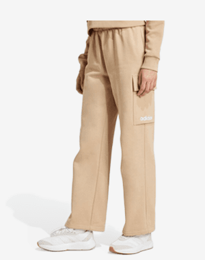 Pantalon beige Adidas avec poche latérale, porté avec un pull beige et des baskets blanches.