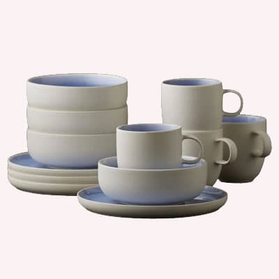 Beiges und blaues Geschirrset mit Tassen, Schalen und Tellern, aufeinander gestapelt und nebeneinander angeordnet.