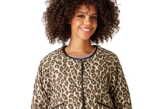 Person mit lockigem Haar trägt Jacke mit Leopardenmuster, Vorderansicht
