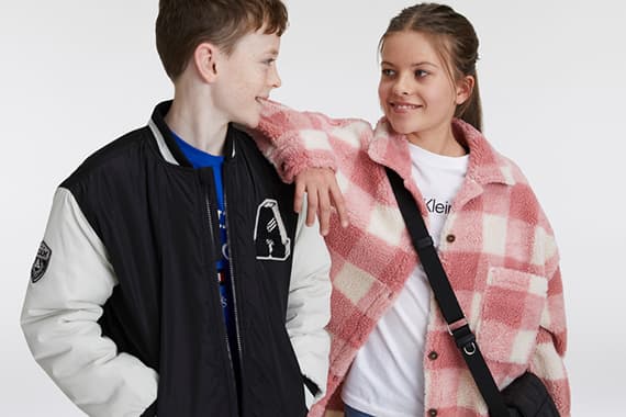 Zwei Holzstühle mit Kissen und kleinem Tisch auf rundem Teppich in hellem Raum mit Pflanzen.