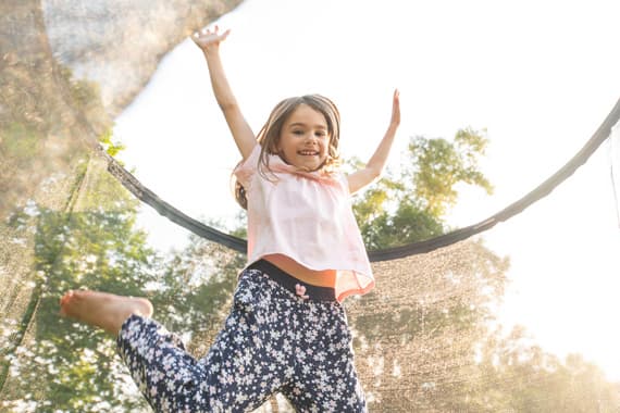 Zwei Holzstühle mit Kissen und kleinem Tisch auf rundem Teppich in hellem Raum mit Pflanzen.