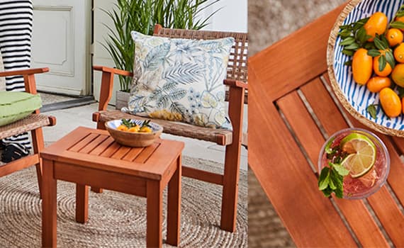 Gedeckter Gartentisch mit bunten Tellern, Schalen und Gläsern, gestreiften Sitzkissen und Deko mit Obstkopf-Vase