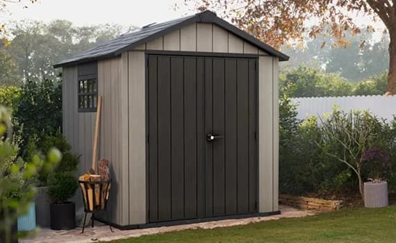 Terrassenpergola mit hellem Sonnensegel über Lounge-Sofa und Tisch mit Tablett vor modernem Haus im Garten