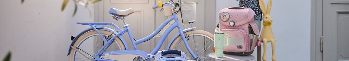 Person in kariertem Hemd und Jeans sitzt im Garten zwischen Pflanzen und Blumen, trägt weiße Handschuhe.