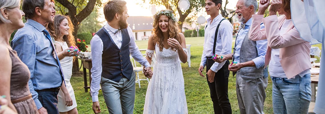 Hochzeitspaar an der Hand, läuft durch Spalier von Gästen im Garten bei einer Feier im Freien