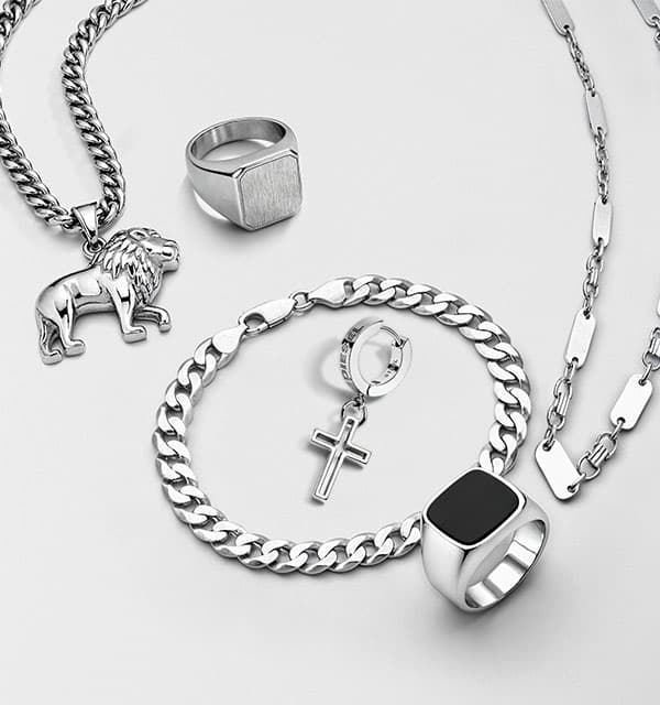Herren-Schmuckset mit Ketten, Löwenanhänger, Kreuzanhänger, Armband und zwei Ringen auf hellem Hintergrund