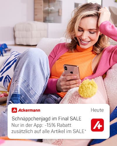 Ackermann Paket – sitzende Person öffnet weißen Versandkarton im Wohnzimmer mit Deko und Blumenständer