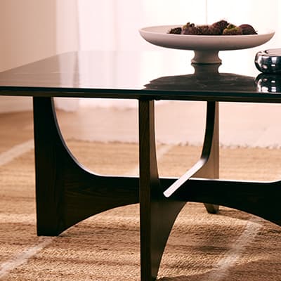 Moderner Couchtisch mit skulpturalem Gestell, darauf eine Schale mit Früchten auf einem Teppich im Wohnzimmer