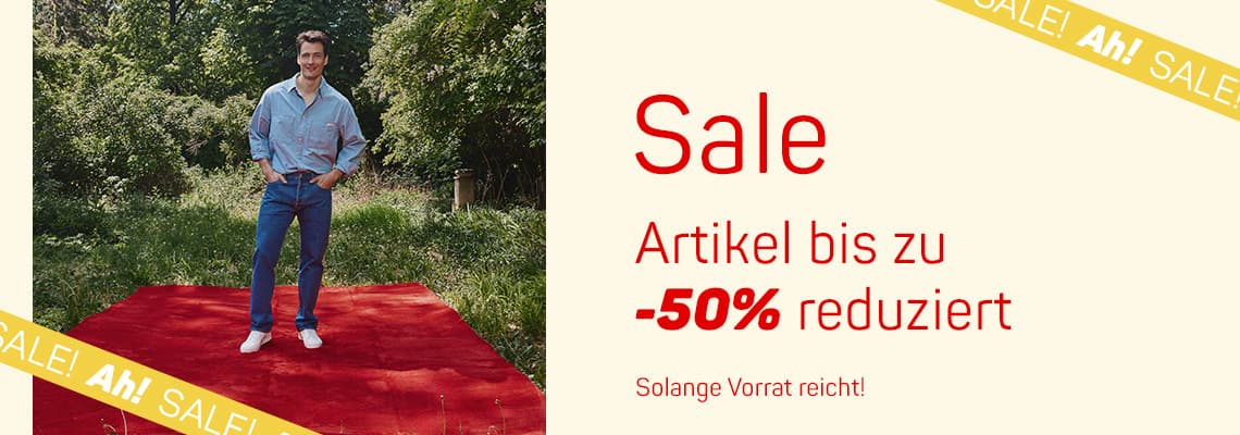 Sale – Artikel bis zu 50 % reduziert, Mann steht auf rotem Teppich im Grünen, Schrift „Solange Vorrat reicht!“