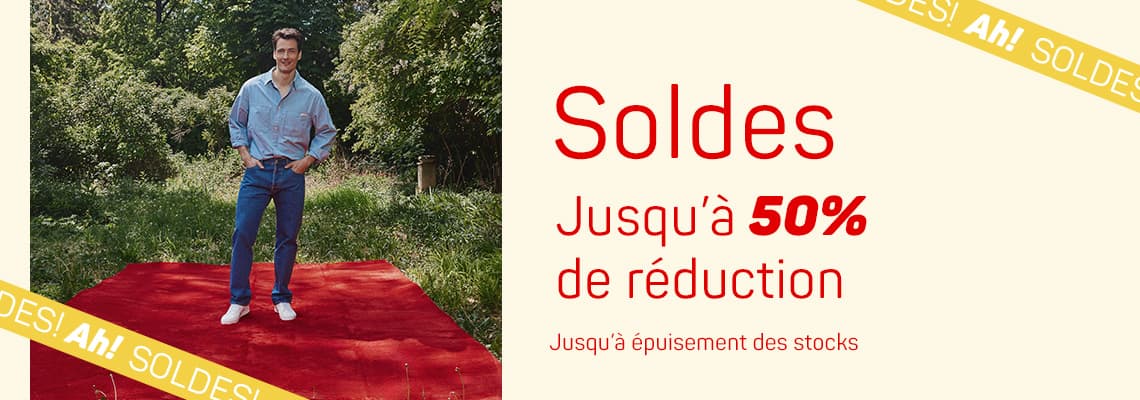 Soldes jusqu’à 50 % de réduction – Homme debout sur tapis rouge en extérieur, texte jusqu’à épuisement des stocks