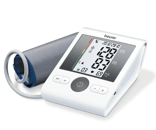 Frau in hellbeigem Strickpullover und passender Mütze hält ihre Hand ans Kinn, blauer Hintergrund