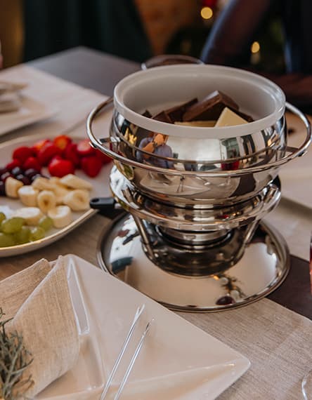 Festlich gedeckter Tisch mit Kerzen, roten Beeren und Geschirr, Besteck und Gläsern auf runden Platzsets