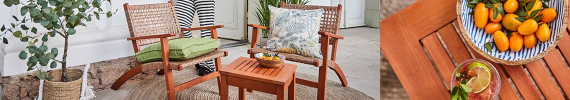 Sommerlich gedeckter Terrassentisch mit bunten Streifen-Kissen und farbigem Geschirr, Tellern und Schalen mit Speisen